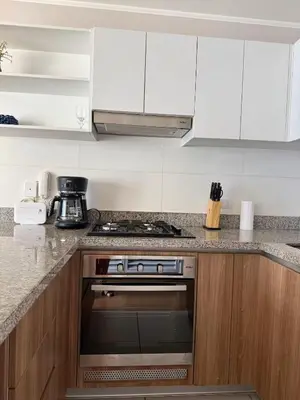 a kitchen with white cabinets and a stove top oven at Departamento Graña in Lima