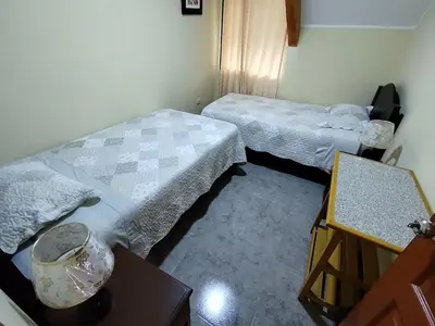 a room with two beds and a table at La Casa de ANNI in Oxapampa