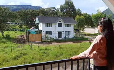 a woman standing on a balcony looking out at a house at La Casa de ANNI in Oxapampa