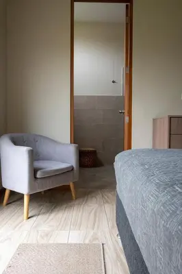 a bedroom with a bed and a chair and a shower at Casa Cieneguilla in Cieneguilla