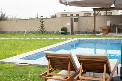 a swimming pool with two chairs in a yard at Casa Cieneguilla in Cieneguilla