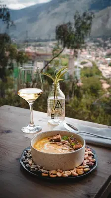 a table with a plate of food and a glass of wine at Tara Vegan Lodge - Sacred Valley in Urubamba