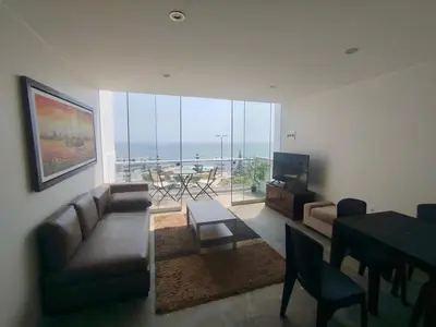 a living room with a couch and a table and a television at Apartment facing Mirador Analí in Punta Hermosa