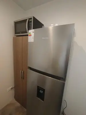 a stainless steel refrigerator with a microwave on top of it at Apartment facing Mirador Analí in Punta Hermosa