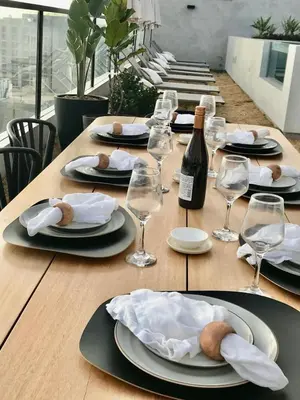 a table with a bottle of wine and plates and glasses at 2BR Apartment with Pool near Larcomar in Lima