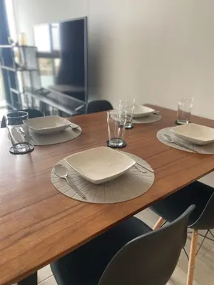 a wooden table with white plates and glasses on it at Barranco Bohemio, Modern and Bright Apartment in Lima