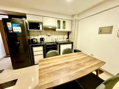 a kitchen with a wooden table and a black refrigerator at Comfort House in Lima