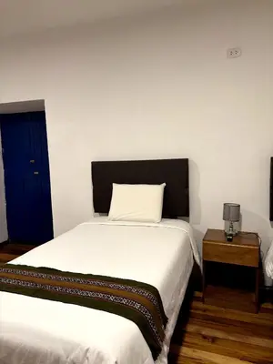 a bedroom with a large white bed with a black headboard at Cusco - Flor de Loto in Cusco