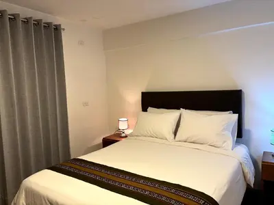 a bedroom with a large bed with white sheets at Cusco - Flor de Loto in Cusco