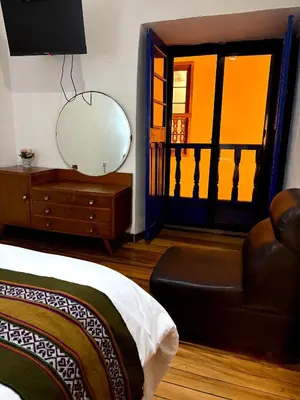 a bedroom with a mirror and a bed and a chair at Cusco - Flor de Loto in Cusco