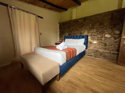 a bedroom with a bed and a stone wall at La Casa de Tay in Urubamba