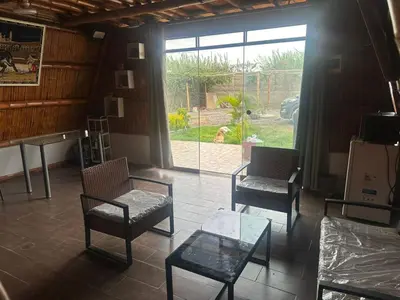 a living room with two chairs and a glass table at Cabaña las Palmeras de Chincha