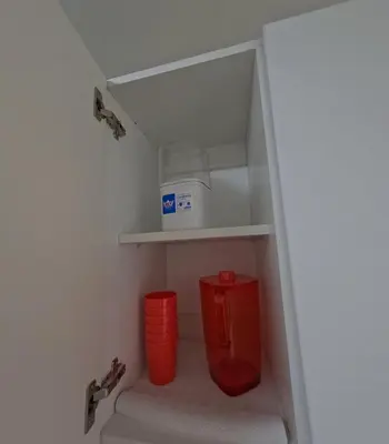a small kitchen with two red buckets and a shelf at Apartamento nuevo en San Bartolo con vista al mar in San Bartolo