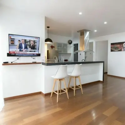 a kitchen with a counter with two stools and a tv at E Larcomarzone FamilyTourist Laundry 3B 503 in Lima
