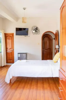a bedroom with a large white bed and wooden floors at Valle Hermoso in San Ramón