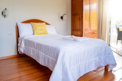 a bedroom with a bed with white sheets and a window at Valle Hermoso in San Ramón