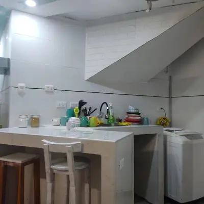 a kitchen with a sink and a counter with stools at La Palmera Apartment in San Bartolo