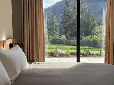a bedroom with a bed and a large window at Earth Tones Tiny Homes & Suites in Ollantaytambo
