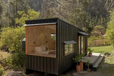 a black tiny house with a large window at Earth Tones Tiny Homes & Suites in Ollantaytambo