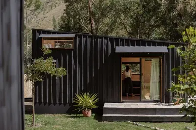 a black house with a person standing in the doorway at Earth Tones Tiny Homes & Suites in Ollantaytambo