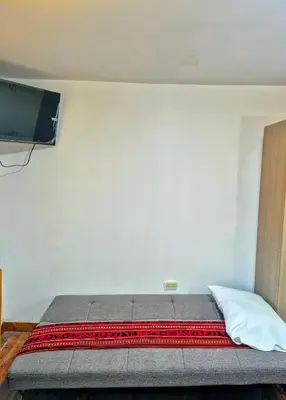 a bedroom with a bed with a tv on the wall at Loft Rústico 03 en Valle Sagrado in Urubamba