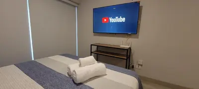 a bedroom with a bed with a chair and a television at Loft de Luxe - cerca a San Borja & San Isidro in Lima