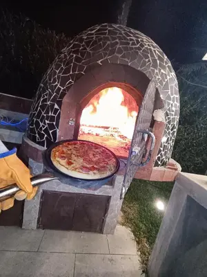 a pizza is being cooked in an outdoor oven at Hermosa casa con piscina privada in Asia