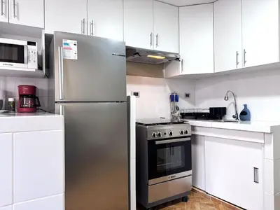 a kitchen with white cabinets and a stainless steel refrigerator at Peruvian Apartments La Angostura in Ica