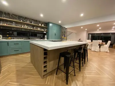 a kitchen with green cabinets and a large island with stools at Steinhaus - Nature, calm and comfort in Oxapampa