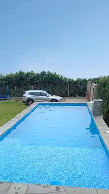 a blue swimming pool with a car in the background at Casa de campo Cieneguilla Vista Bonita in Cieneguilla