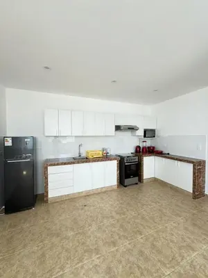 a kitchen with white cabinets and a black refrigerator at Departamento cerca a la playa 202 in Punta Negra