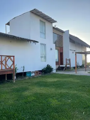 a white house with a lawn in front of it at Refugio 55 Casa de Playa en Chincha, Frente al mar in Chincha Baja