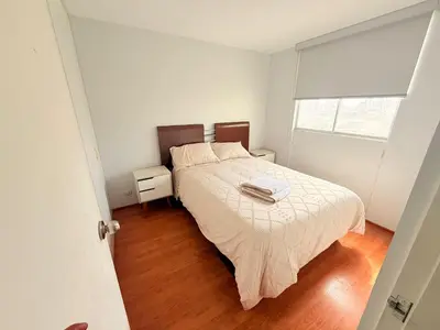 a white bedroom with a bed and a window at Casa Lima Brasil in Lima