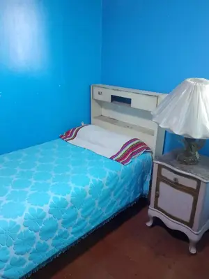 a blue room with a bed and a lamp on a nightstand at San Juan in Lima