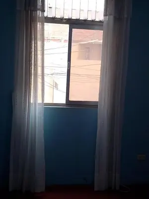 a window with white curtains in a blue room at San Juan in Lima