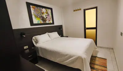 a bedroom with a bed and a painting on the wall at mini departamento Andahuaylas in Andahuaylas