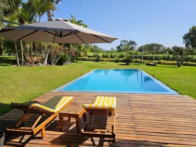 two chairs and an umbrella next to a swimming pool at Spacious 4BR Country House with Pool in Mala in Asia