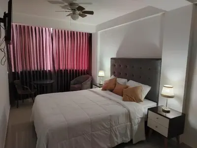 a bedroom with a bed and a table with a chair at Hostal Mirador in Pisco