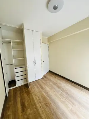 an empty room with white cabinets and wood floors at El Derby in Lima