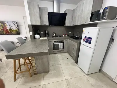 a kitchen with a white refrigerator and a table at Albano Penthouse íntimo piscina y vista al mar in Lima