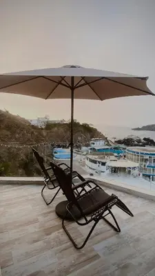 two chairs sitting under an umbrella on a roof at Infinitive view San Bartolo in San Bartolo