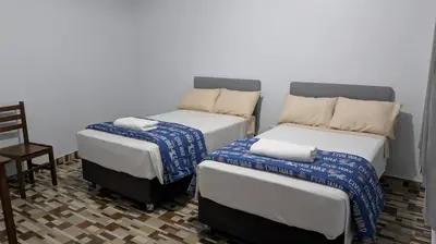 two twin beds in a room with a chair at Aguilar Apaza Family in Machu Picchu