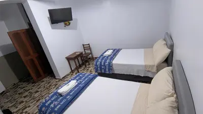 a small room with two beds and a television at Aguilar Apaza Family in Machu Picchu