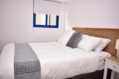 a bedroom with a bed with white sheets and a window at Acogedor Departamento en Centro Histórico de Cusco in Cusco