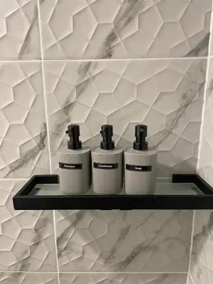 a shelf with three bottles on it in a bathroom at Acogedor Departamento en Centro Histórico de Cusco in Cusco