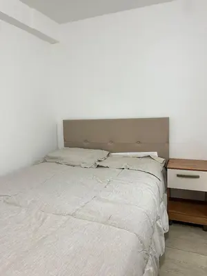 a bedroom with a white bed with a wooden nightstand at Departamento de un solo ambiente in Lima