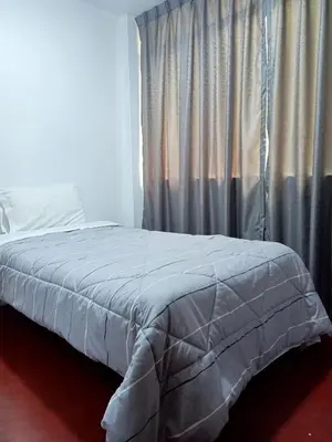 a bed with a gray comforter in front of a window at Departamento 3 dormitorios 4A in Lima