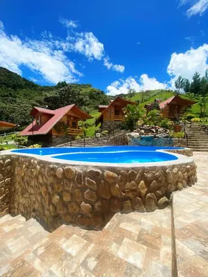 a pool with a stone wall next to a house at Lodge La Arboleda - Oxapampa in Oxapampa