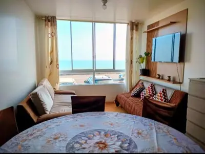 a living room with a table and a large window at Costa 21 Frente al Mar San Miguel in Lima