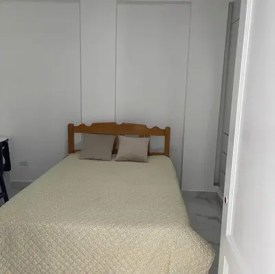 a bed in a room with a white wall at Habitación privada con baño propio cerca de Paracas, Pisco in Pisco